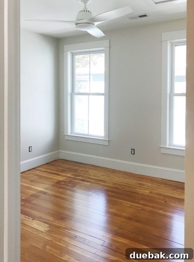 Refinished pine floors in upstairs bedroom with white ceiling fan