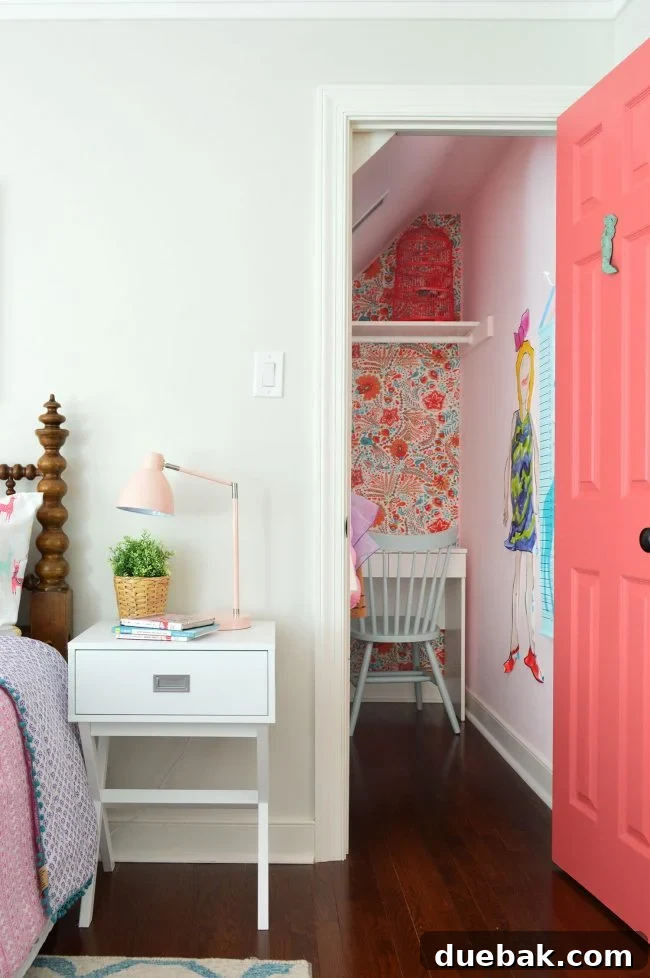 Girls bedroom closet transformed into a creative nook with pink door and fabric wallpaper