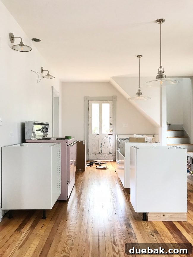 Beach house kitchen with white cabinets, pink stove, and vintage door