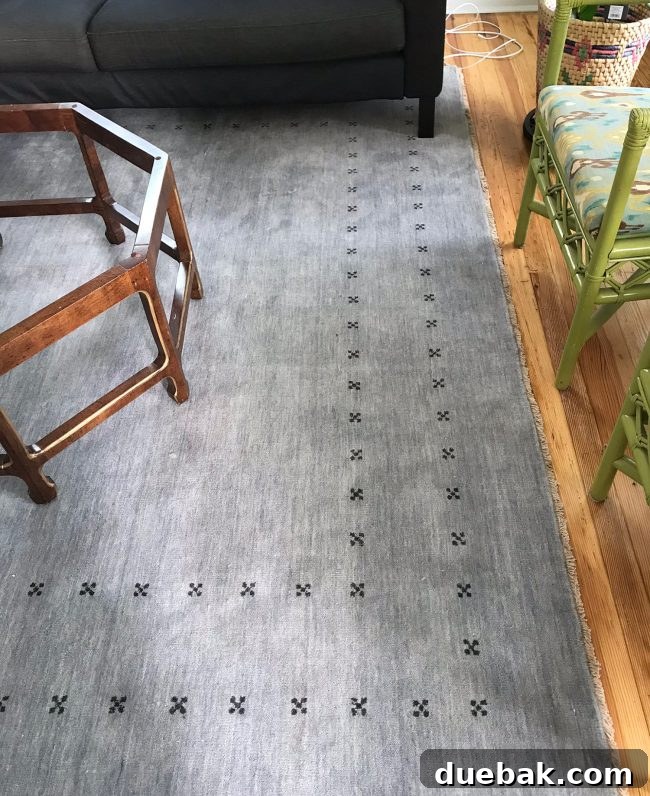 Downstairs living room with blue-gray rug and green chairs awaiting renovation