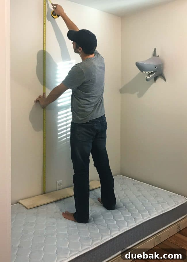 Constructing Bespoke Bunk Beds 12 John carefully measuring and assessing the ideal height and placement for the top bunk platform in the small room.