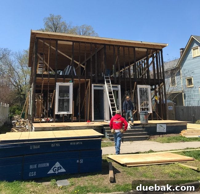 Duplex with roof framing and plywood installed, showing ongoing construction