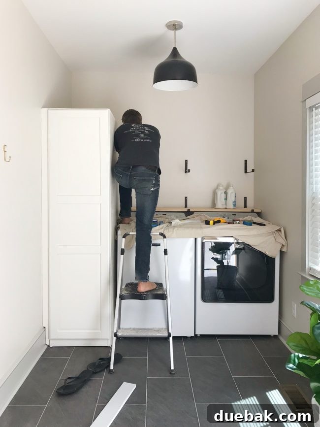 Ikea Cabinet Water Heater Makeover 21 john leaning over top loading washer to screw in shelf brackets