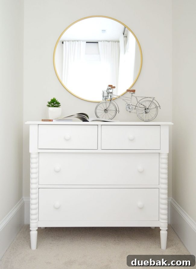 Jenny Lind dresser with a round brass mirror and bicycle art in A's bedroom