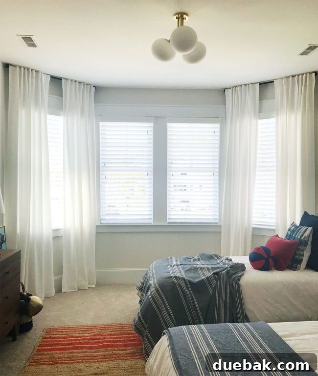 Before photo of J's bay window with separate curtain rods over each section, looking disjointed