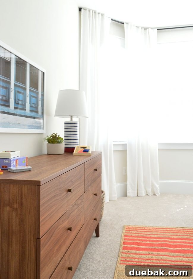 Dresser with art and lamp in J's bedroom, complementing the overall color palette