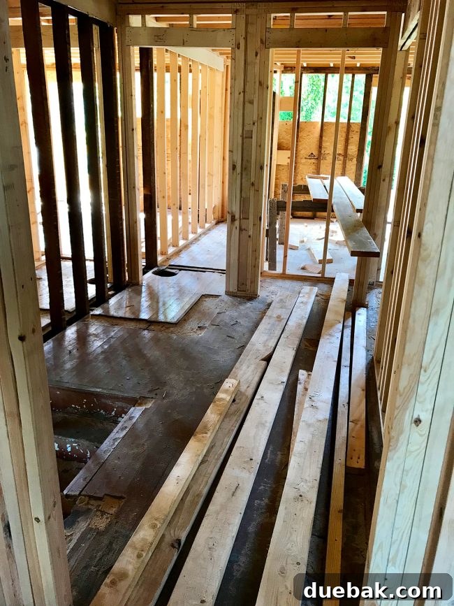 Another view of the expanded upstairs landing, looking towards the front bedroom doorway, with the old wall's footprint visible on the floor, emphasizing the increased space.