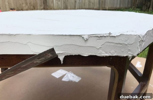 Scraping off hardened Ardex drips from the bottom edge of the table