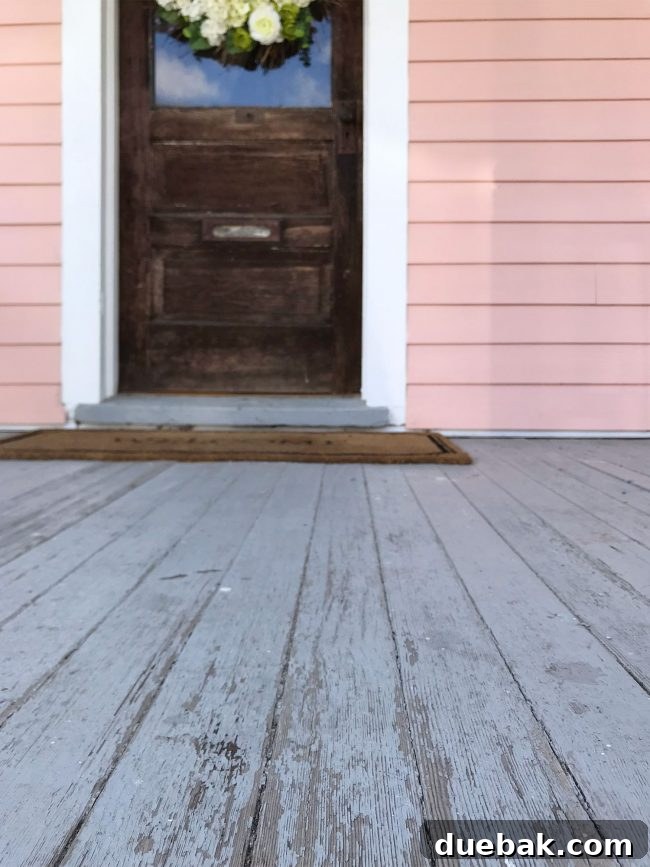 Rough-looking porch and front door of the pink house