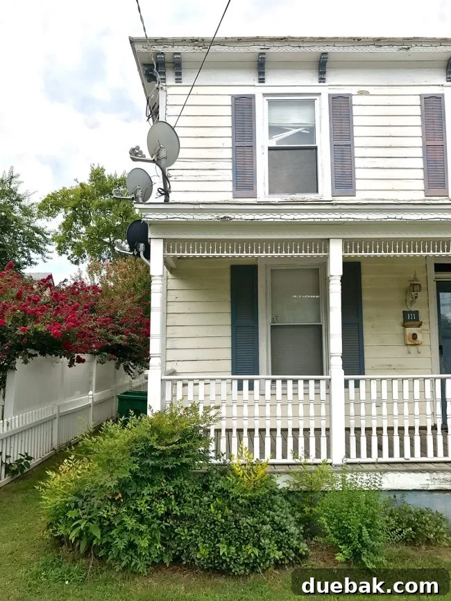 Side view of the duplex before renovation, showing the roof and existing siding with a satellite dish.