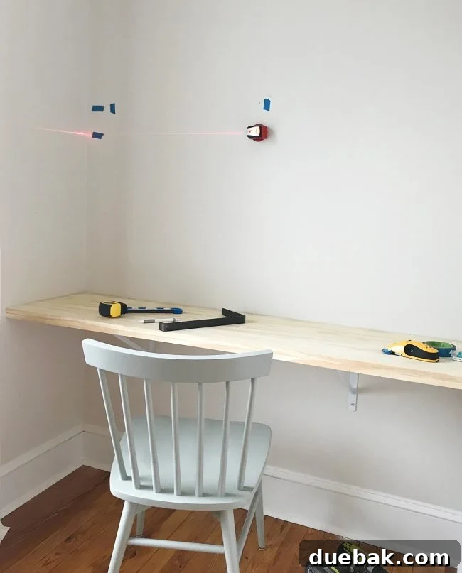 Using a laser level to mark shelf bracket positions on the wall
