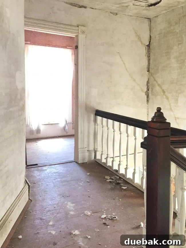 Beach house upstairs landing before renovation with crumbling drywall and painted floor