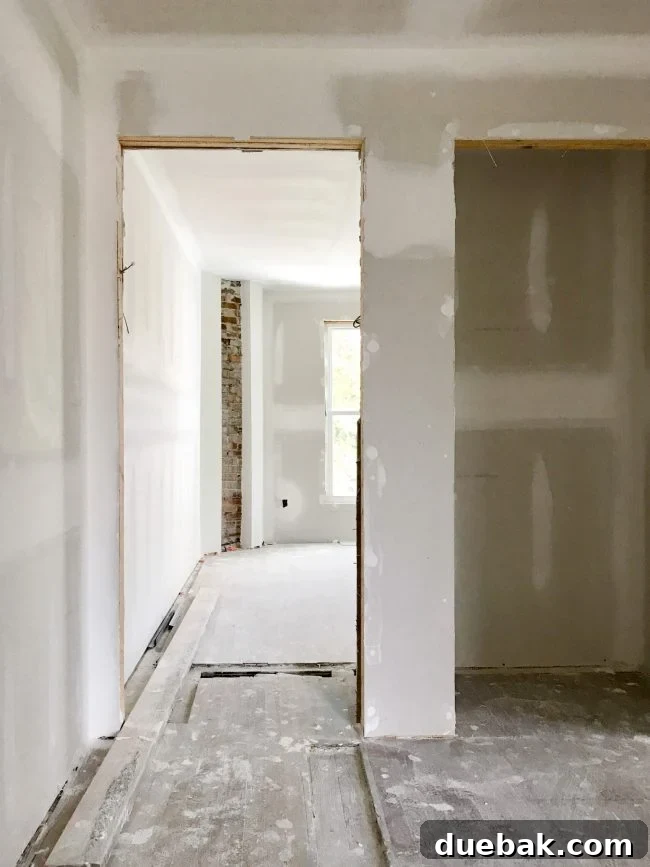 The Duplex Takes Shape Drywall And Video Tour Reveal 13 Upstairs landing with new window and exposed brick in bedroom