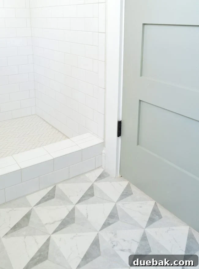 Modern bathroom with marble-look floor tile and white subway wall tile, featuring a blue-green door.