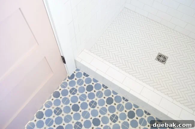 Elegant bathroom with patterned floor tile, white walls, and a warm gray door.