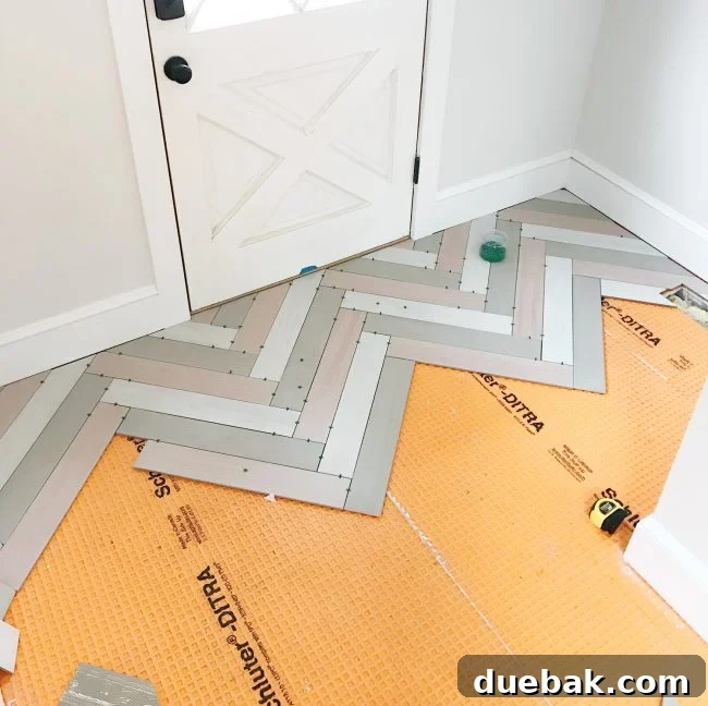 Progress shot of herringbone mudroom floor, showcasing the three different tile colors.
