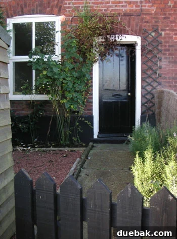 Quintessential English Cottage Garden & Street View Charming street view of an English cottage with a picturesque garden and welcoming front door, hinting at its historic beauty.