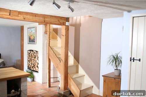 Open Living Space: Kitchen to Living Room Open plan living area in an English cottage, showing the transition from kitchen to living space with a clever fireplace feature.