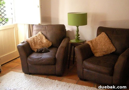 Cozy Living Room with Retro Green Lamp Charming English cottage living room with comfortable seating and a striking retro green lamp from Habitat, adding a modern touch to the cozy interior.