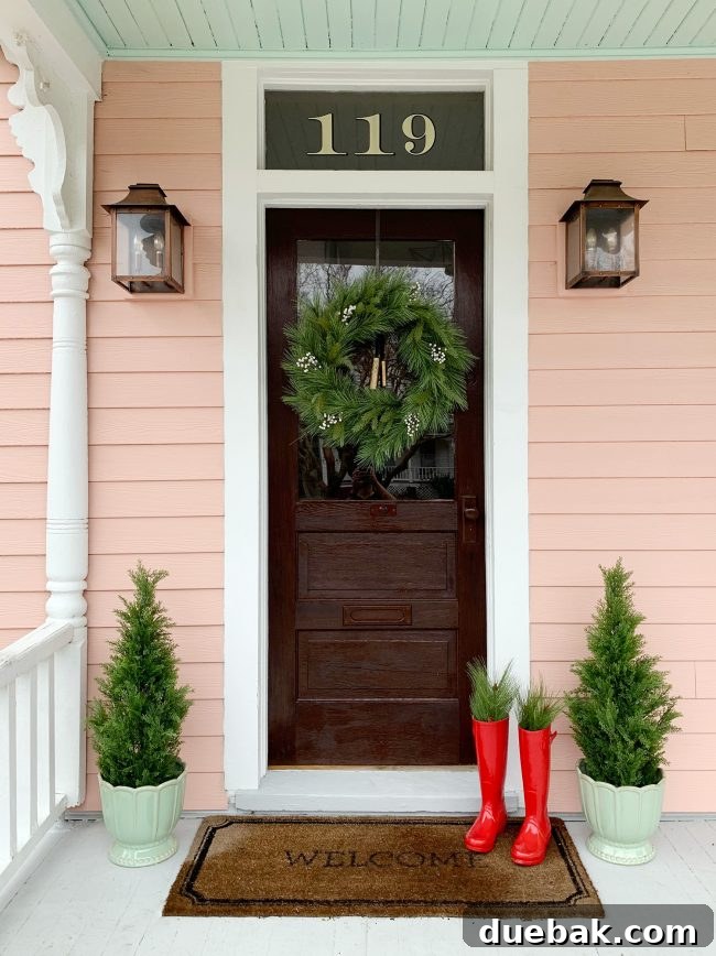 Double the Sparkle: Holiday Decorating at Home and the Beach 14 Red boots filled with faux evergreen branches and small faux trees on a beach house porch.
