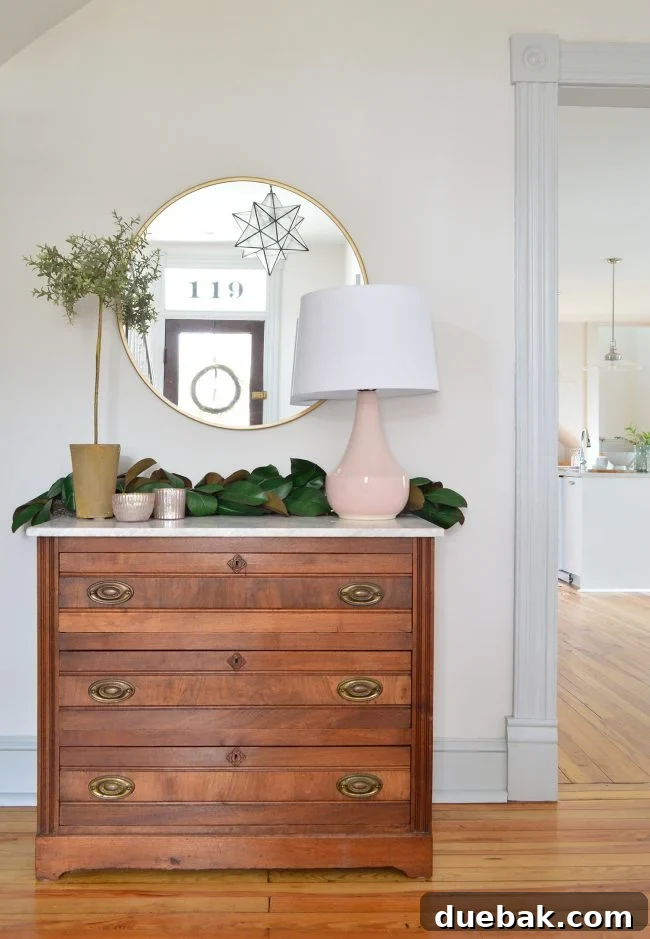 Double the Sparkle: Holiday Decorating at Home and the Beach 15 Faux magnolia garland draped over a marble-top dresser in a beach house entryway.