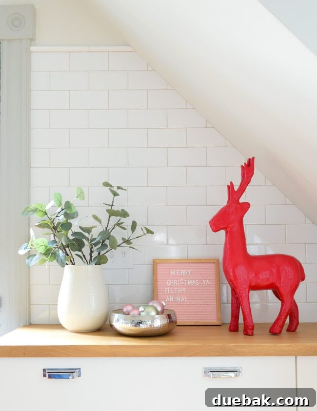 Double the Sparkle: Holiday Decorating at Home and the Beach 18 A kitchen decorated with red reindeer, a bowl of ornaments, and a letter board with a Home Alone quote.