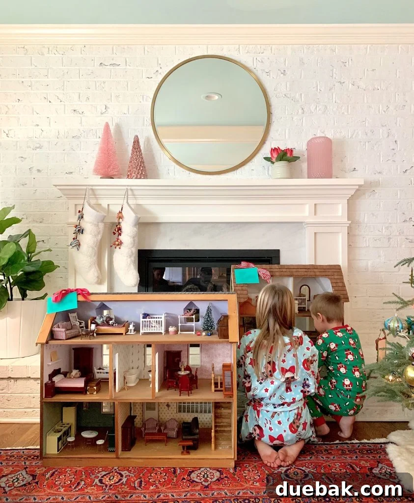 Two children playing with new dollhouses on Christmas morning, surrounded by gift wrap.
