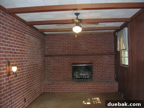 Before shot of a dark, outdated den with heavy paneling, contributing to a 'hunting lodge' aesthetic in a Richmond brick ranch house.