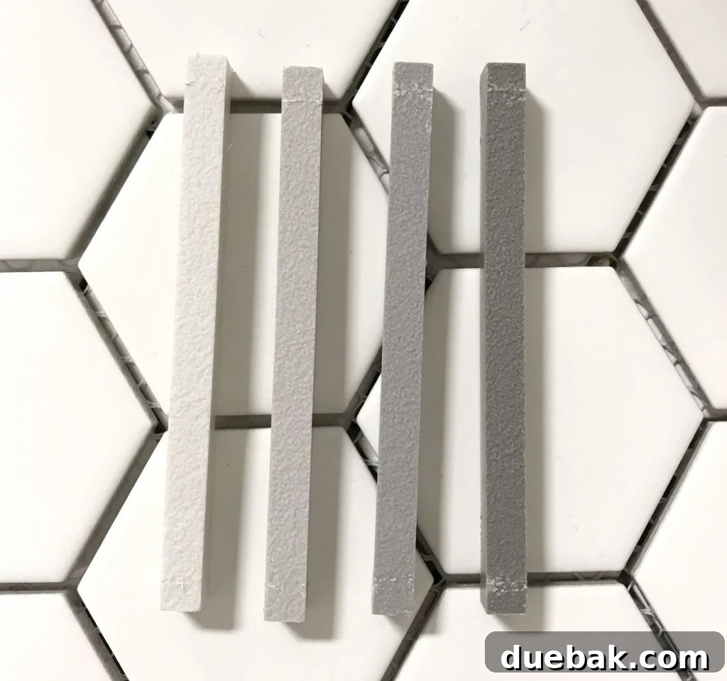 Finding Your Best Grout: Tips for Perfect Color Selection 12 four mapei grout sample sticks atop white hex tile going from light to dark