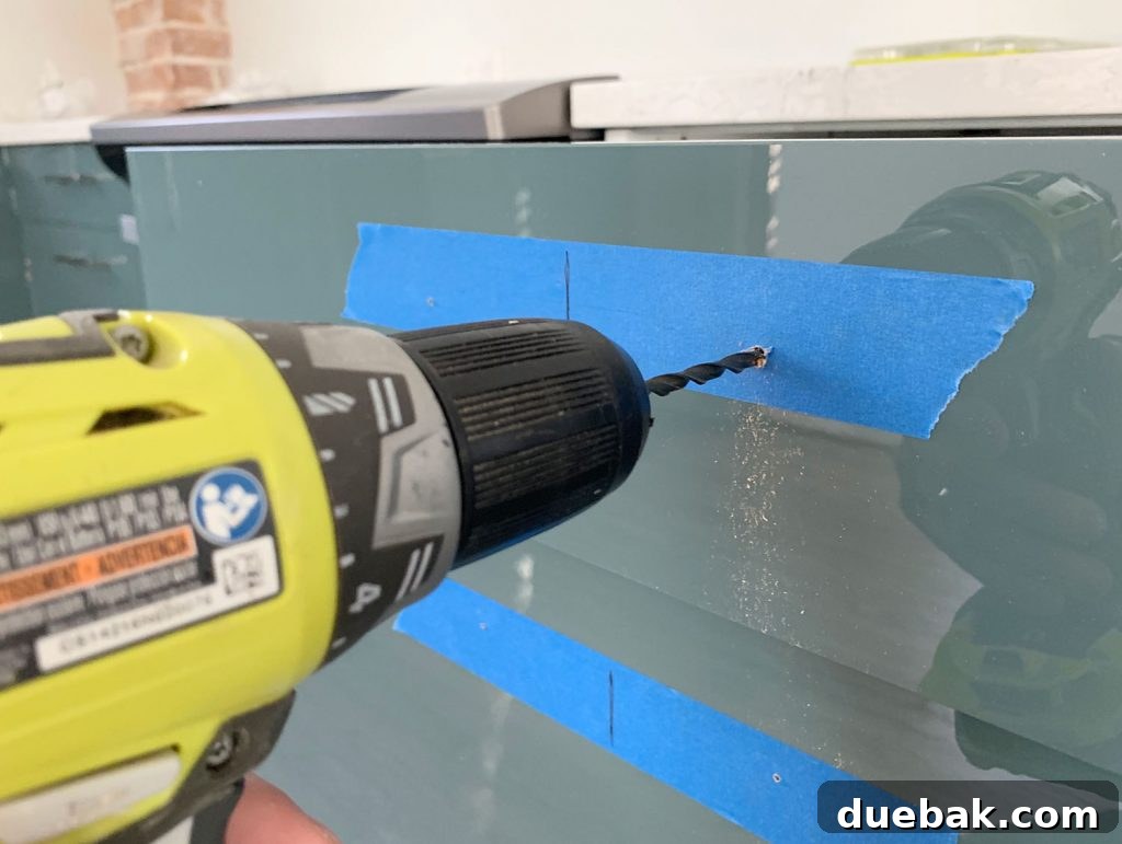 Drilling Larger Hole Through Drawer Front For Cabinet Hardware using the pilot hole as a guide.