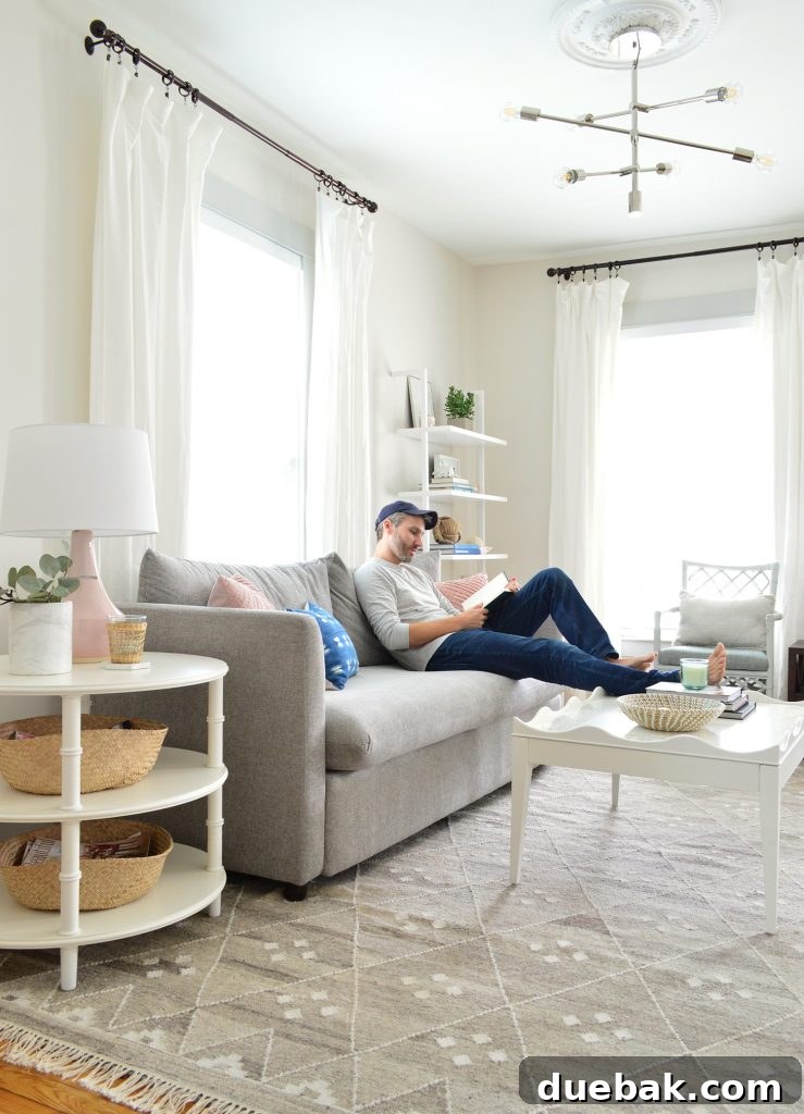 John reading on the gray sofa with his feet comfortably resting on the scalloped white coffee table, demonstrating its comfort.