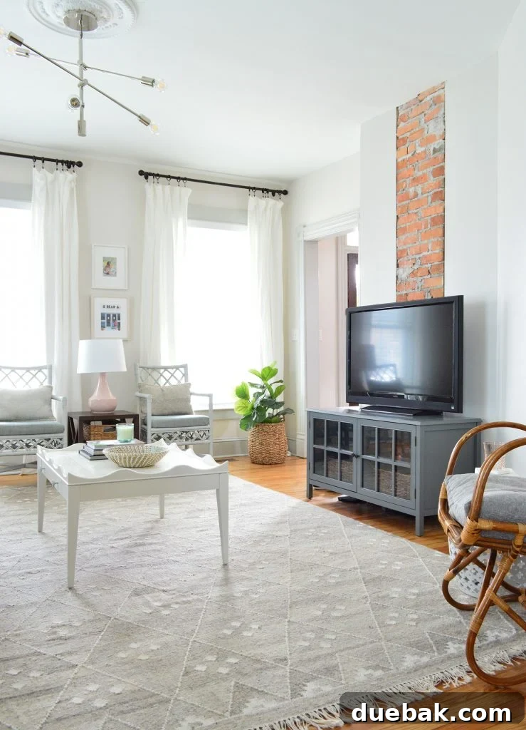 Brick chimney with TV on a dark gray media cabinet surrounded by neutral furnishings, showcasing the updated layout.