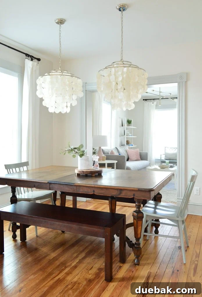 Vintage dining table illuminated by two new capiz chandeliers from our lighting line, enhancing the dining room's elegance.
