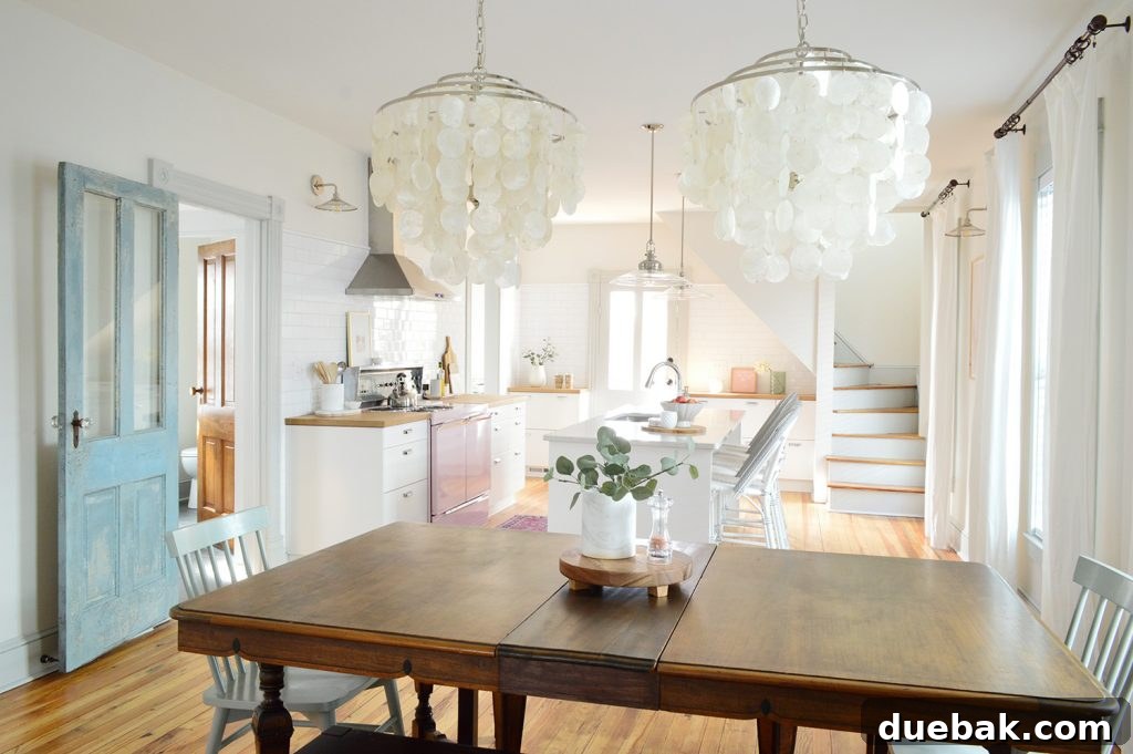 View into the beach house kitchen through the dining room with new capiz chandeliers, showcasing an open-concept living space.