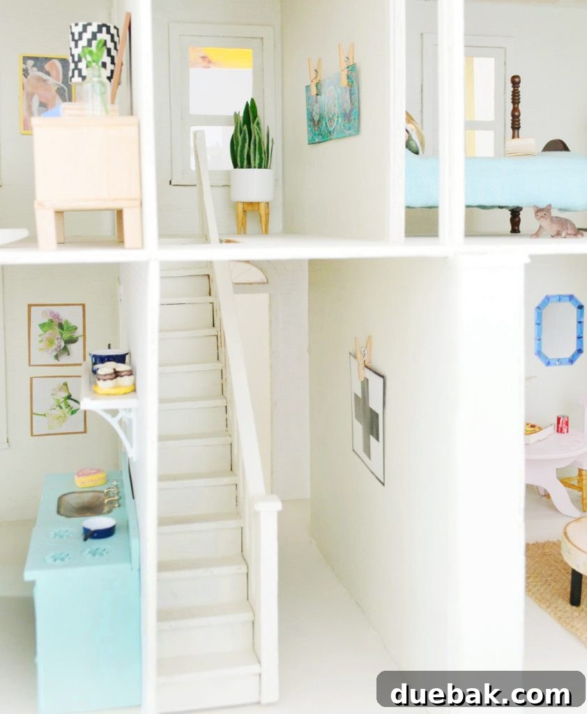 The downstairs foyer and upstairs landing of the dollhouse, showing miniature art and a plant in a stand.