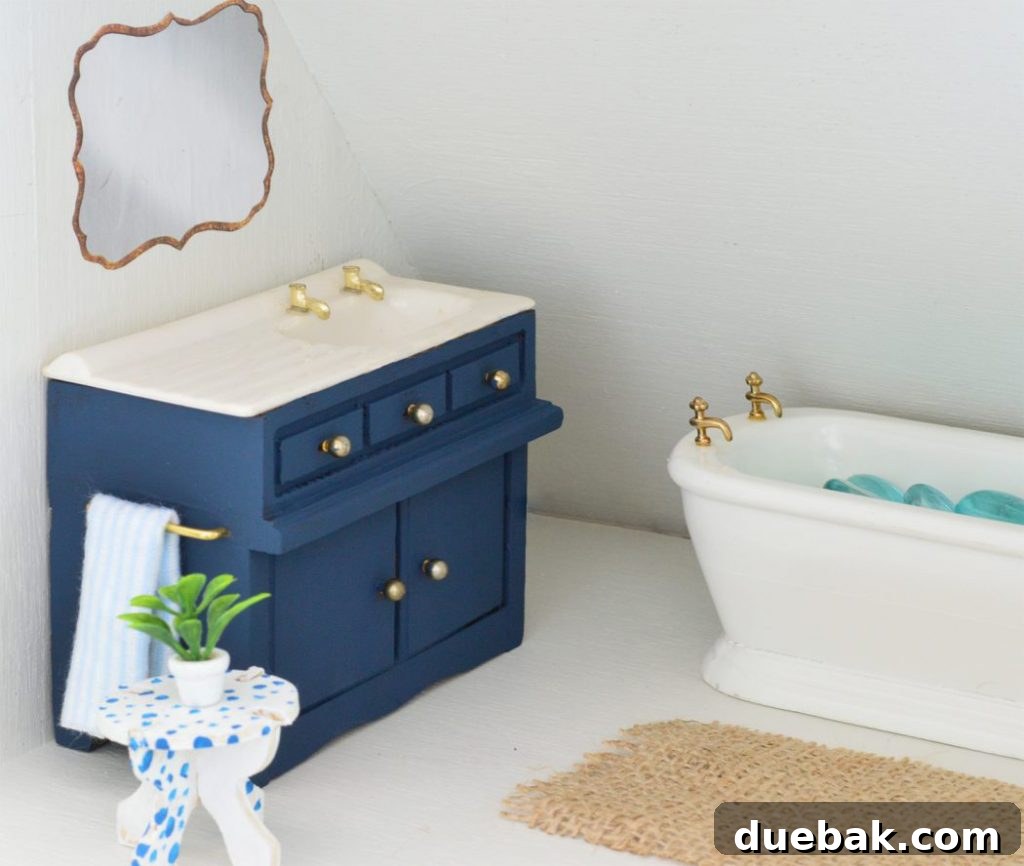 The dollhouse bathroom sink with a DIY hand towel, a magazine cutout mirror, and charming gold fixtures.
