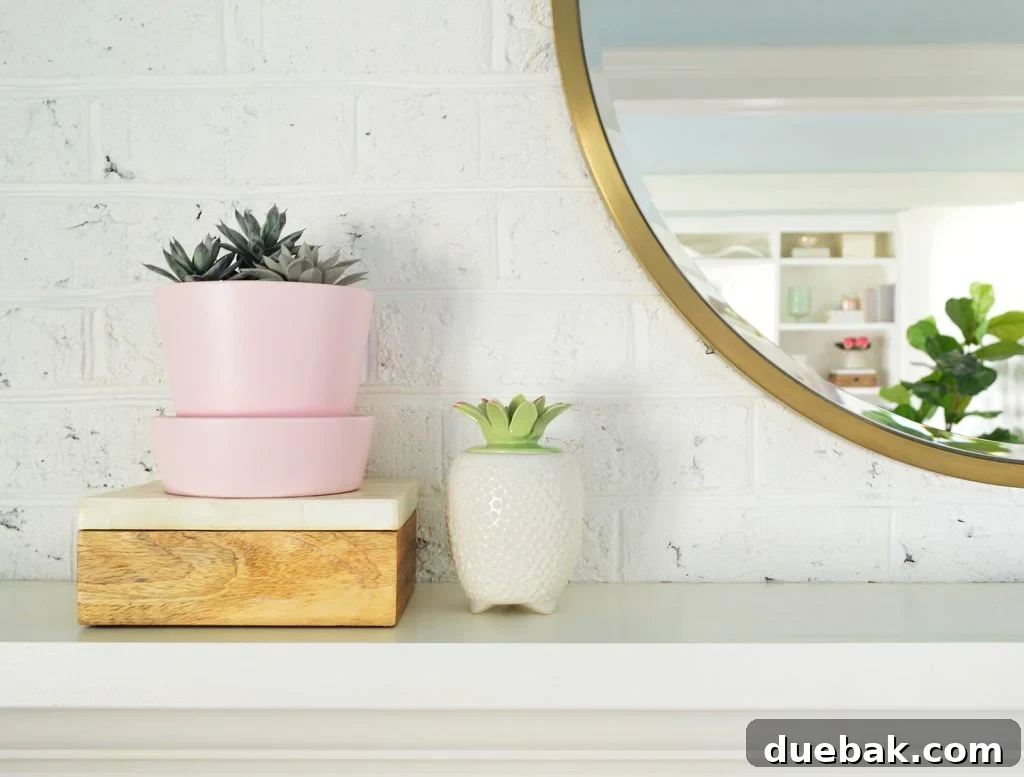 Faux succulents on living room fireplace mantle next to round gold mirror
