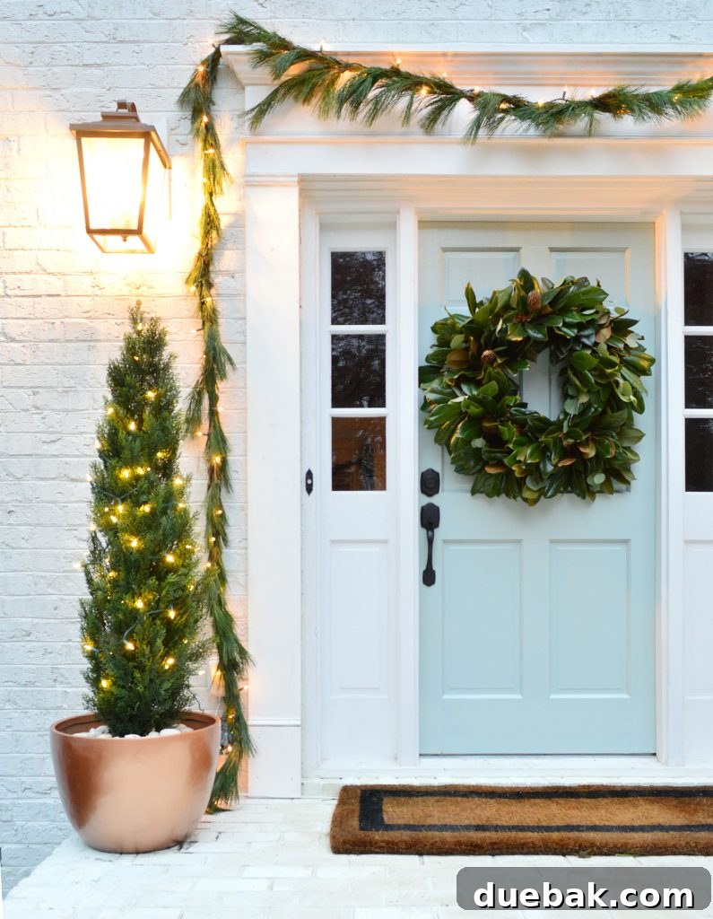 Front porch Christmas decor with a real garland, real magnolia wreath, and faux bushes