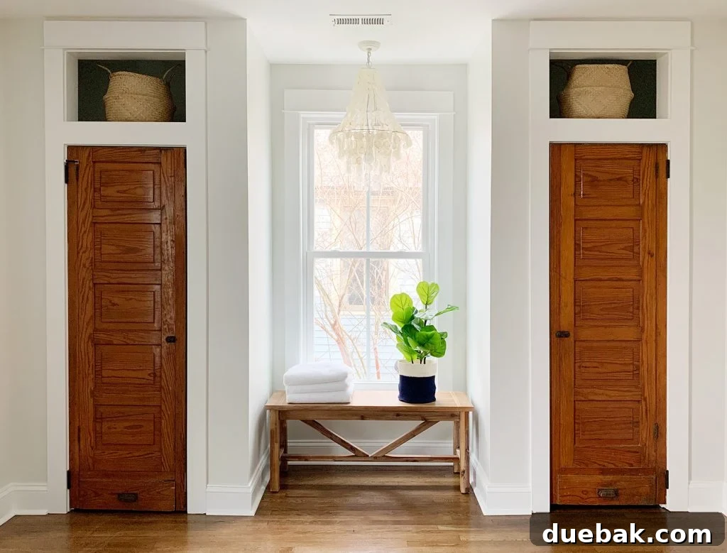Faux fiddle leaf fig on bench between two closets under chandelier