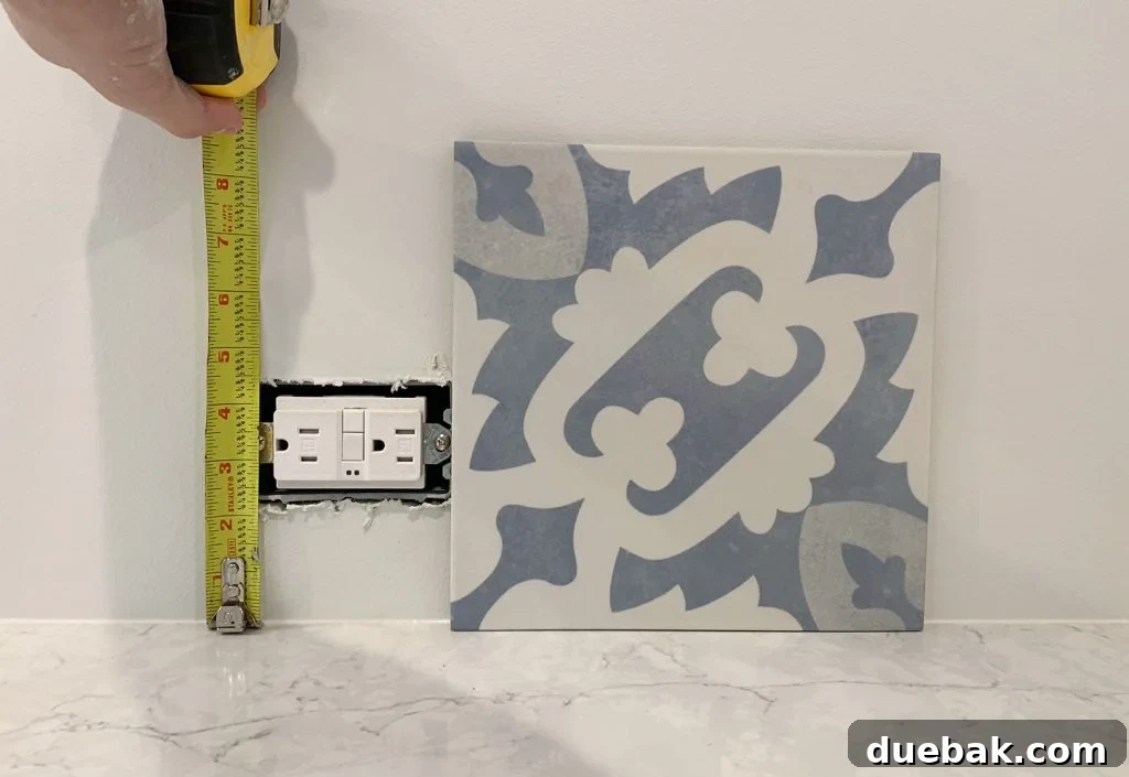 Checking Backsplash Tile Against Electrical Outlet in Kitchen During Planning