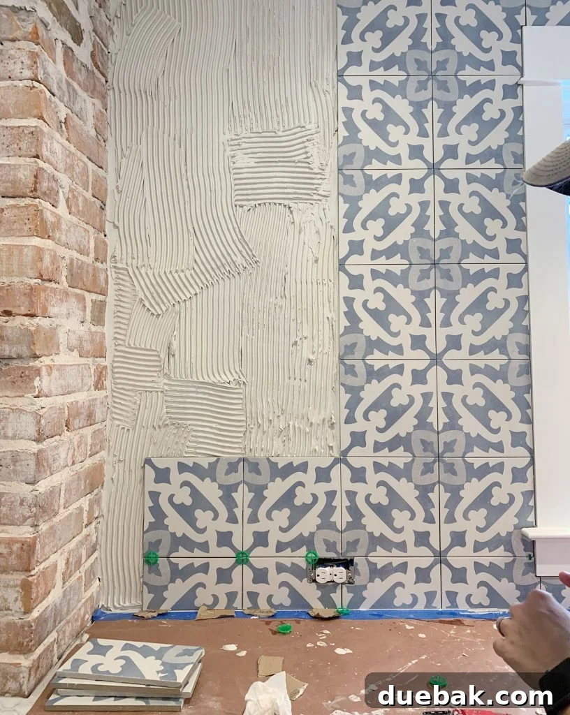 Detail of Backsplash Installation Progress with Blue Patterned Tile and Outlet Cut