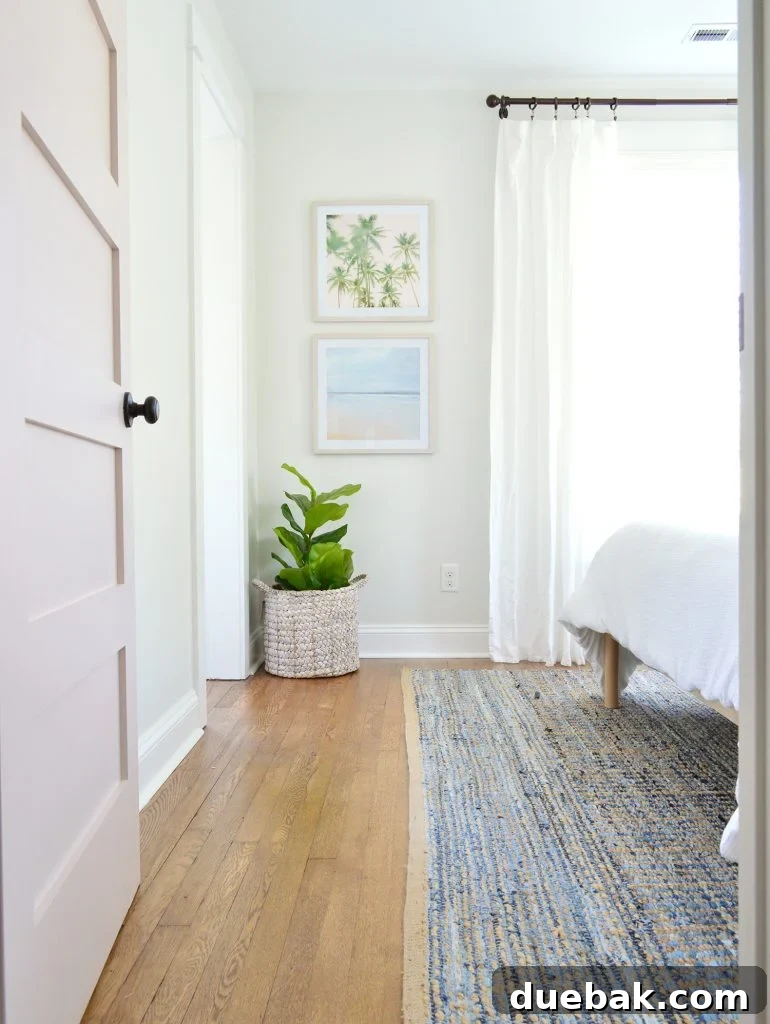 Our Airbnb Bedroom and Bathroom Makeover Full Reveal 13 Front bedroom after renovation, showcasing a faux fig plant, a curated artwork set, flowing curtains, and charming pink doors.