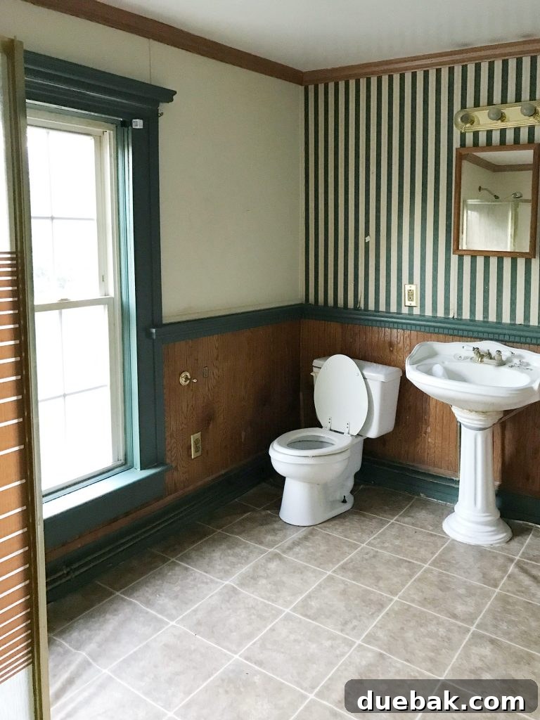 Our Airbnb Bedroom and Bathroom Makeover Full Reveal 18 Before shot of a bathroom with bubbled and loose vinyl flooring, indicating significant underlying water damage.