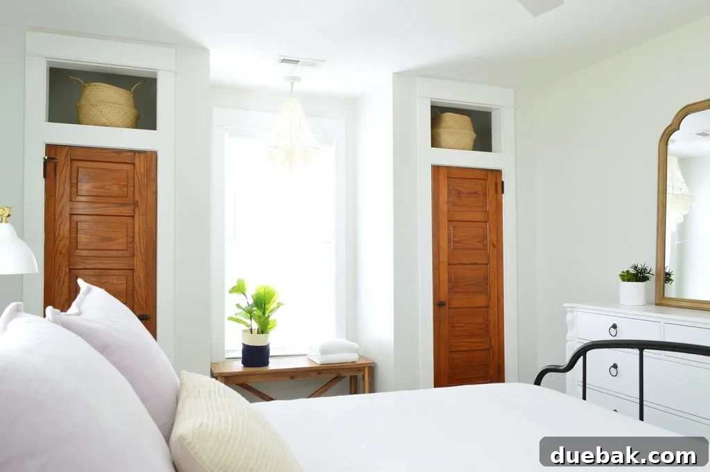 Our Airbnb Bedroom and Bathroom Makeover Full Reveal 8 Interior view of the main bedroom, highlighting the cozy bed, decorative elements, and original salvaged closet doors.