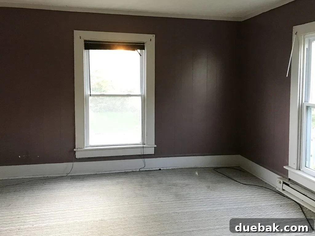 Our Airbnb Bedroom and Bathroom Makeover Full Reveal 10 Before shot of the main bedroom, depicting dilapidated conditions with plastic paneling, old carpeting, and hidden damage.