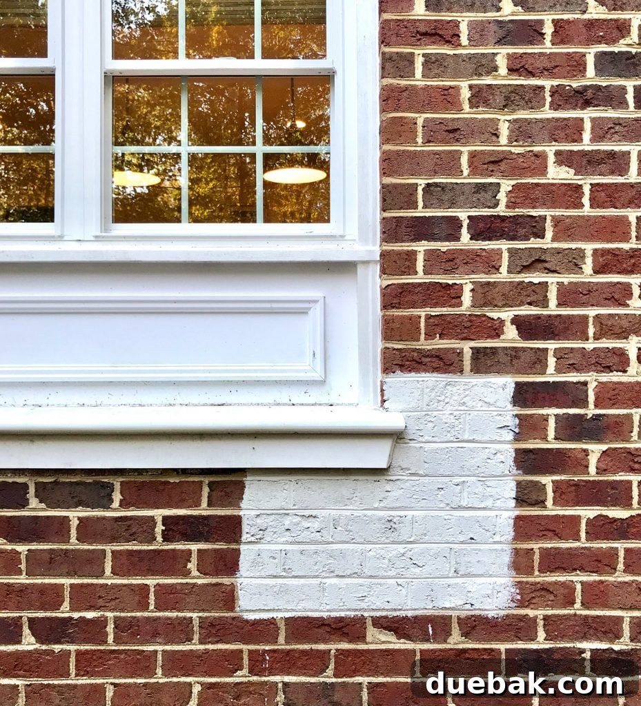 Large white paint sample on blotchy maroon and brown brick