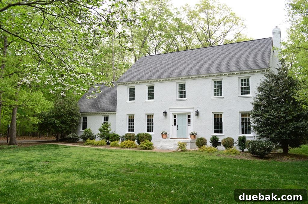 Beautiful white painted brick house with lush green landscaping