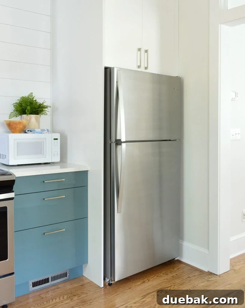 Dual Kitchen Transformations: Our Airbnb's Story 14 Built-in refrigerator cabinet in an Ikea kitchen with blue cabinets, offering a seamless and integrated look.
