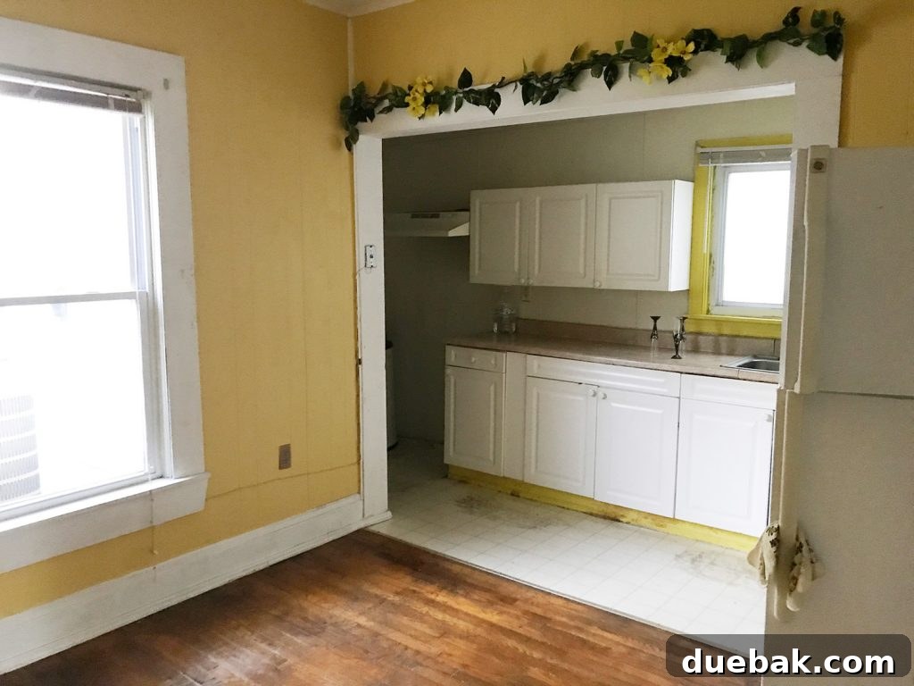 Dual Kitchen Transformations: Our Airbnb's Story 21 Before photo of a large yellow room with an old fridge and some faux greenery.
