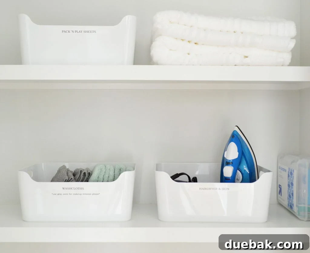Labeled white bins in the duplex linen closet, promoting clear organization.